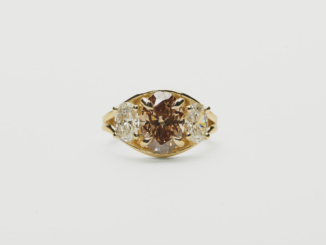  three stone ring, oval brown diamond and oval diamond side stones set in a split shank yellow gold setting