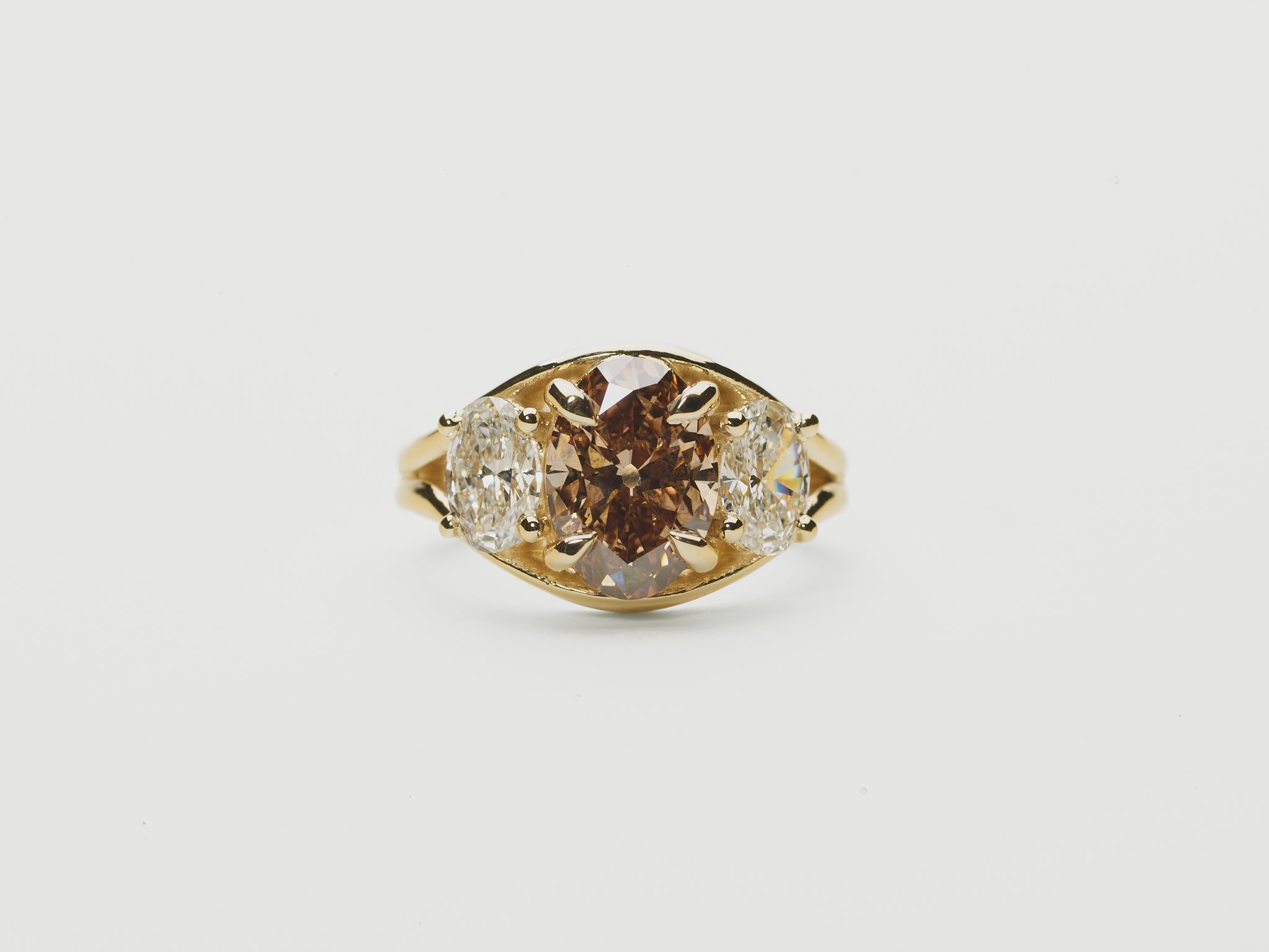  three stone ring, oval brown diamond and oval diamond side stones set in a split shank yellow gold setting