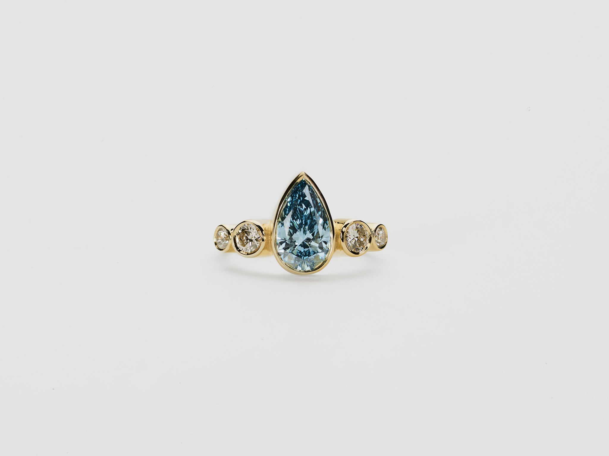 Gold ring with a teardrop-shaped blue diamond  centre stone with round diamonds