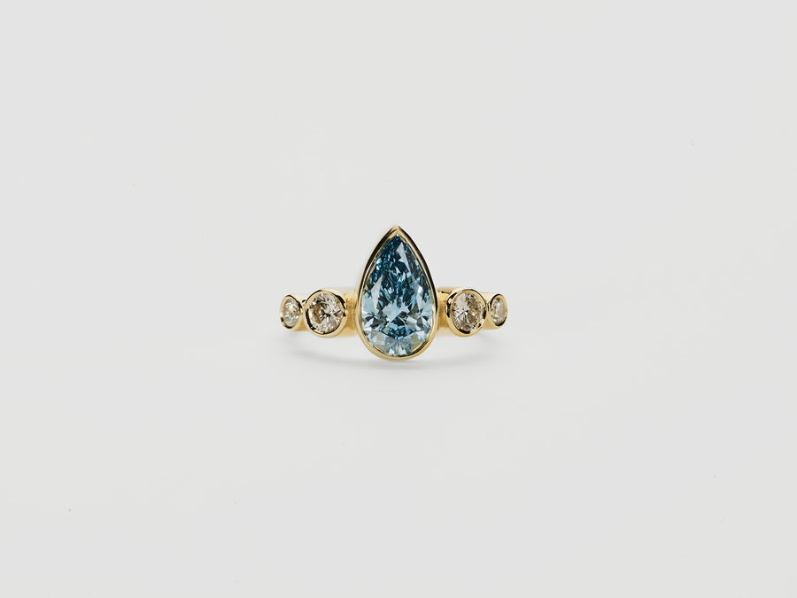 Gold ring with a teardrop-shaped blue diamond  centre stone with round diamonds
